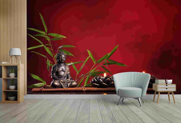 Buddha in meditation with burning candle and bamboo leaf on red background.
